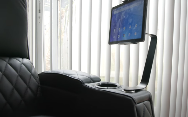 Black leather recliner chair fully reclined in zero gravity position in front of living room window with blinds