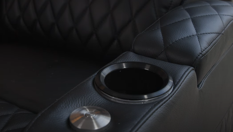 Close-up detail of black leather recliner armrest with cup holder and LED accent lighting
